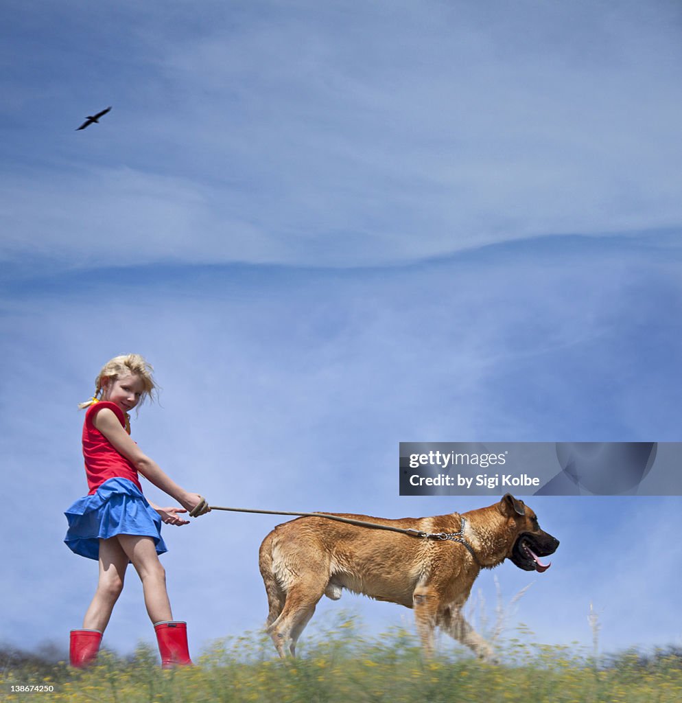 Young blonde girl walking with dog