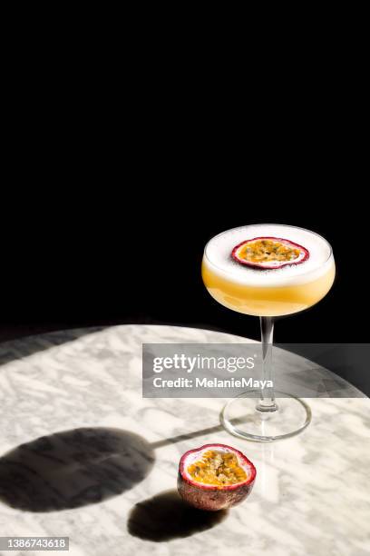 passion fruit cocktail aperitif in coupette glas with fresh fruit and foam - passievrucht stockfoto's en -beelden