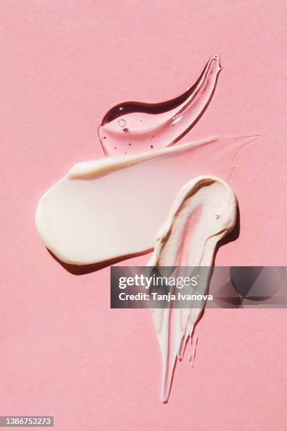 textured multi colored smears of cosmetics on pink background. samples of creams, face mask, face gel, serum. flat lay, top view. - face serum stock pictures, royalty-free photos & images