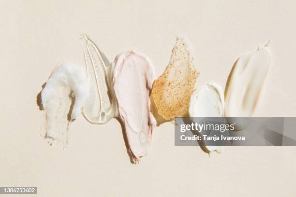 textured multi colored smears of cosmetics on a beige background. samples of creams, face mask, scrub with exfoliating particles, face gel, serum. flat lay, top view. - scrubs stock pictures, royalty-free photos & images