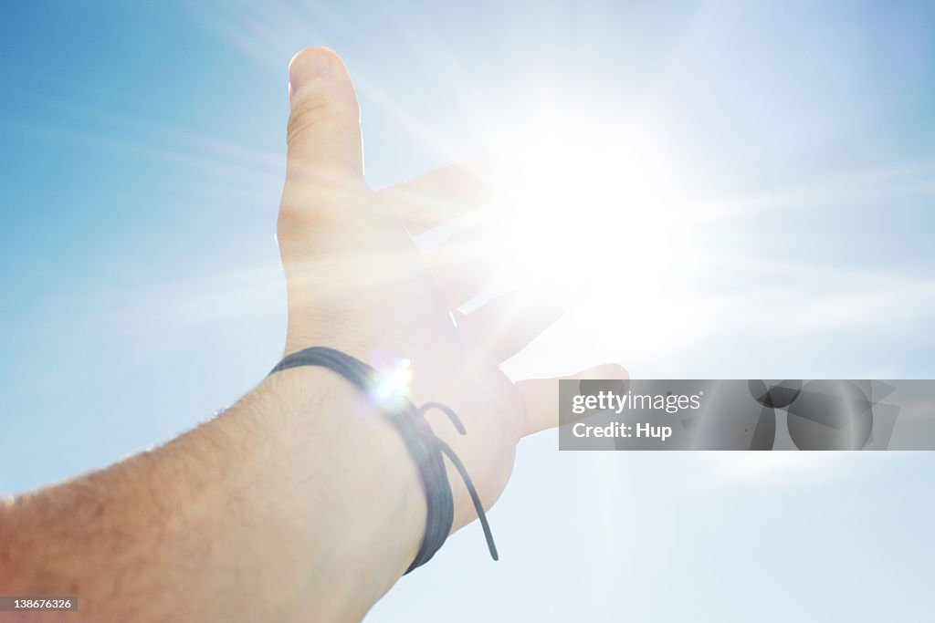 Mans hand reaching for sun