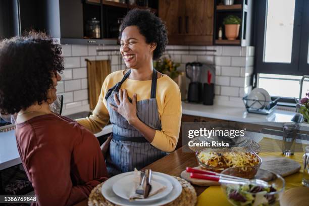 two woman enjoying lunch at home - woman cooking stock pictures, royalty-free photos & images