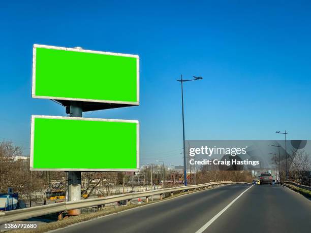 medium size green screen chroma key marketing advertisement billboard in city centre urban road freeway highway environment targeting adverts at consumers, retail shoppers, commuters and tourists as they drive past in their cars. - billboard highway stock-fotos und bilder