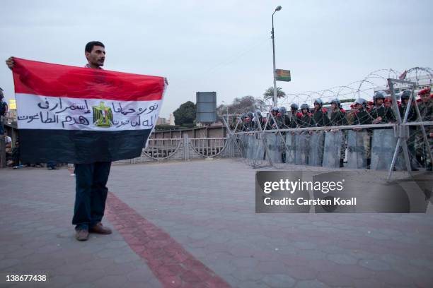 Protester shows the Egyptian national flag to soldiers staying behind a barbed wire barrier by the army forces to stop protesters after a...