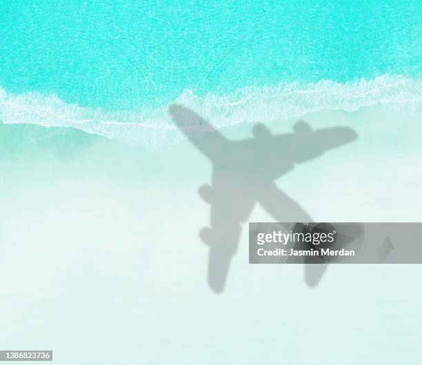 aircraft shadow flying over an idyllic beach scene - airplane shadow stock pictures, royalty-free photos & images