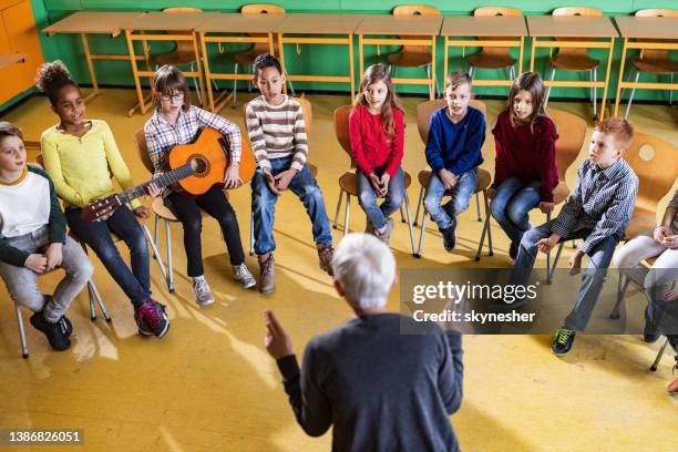 große gruppe von grundschülern, die eine musikklasse mit ihrem lehrer haben. - music class stock-fotos und bilder