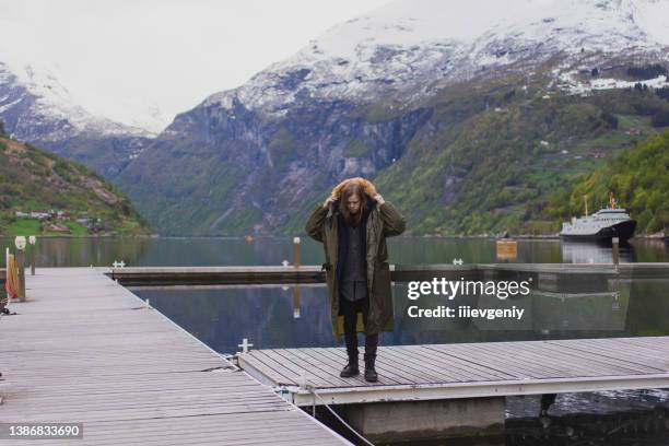 man silhouette on background of mountains in norway. landscape with fjords. tourist in rain coat against geiranger fjord. snow on mountain. scandinavia. north nature. experiental travel. raincoat - more og romsdal bildbanksfoton och bilder