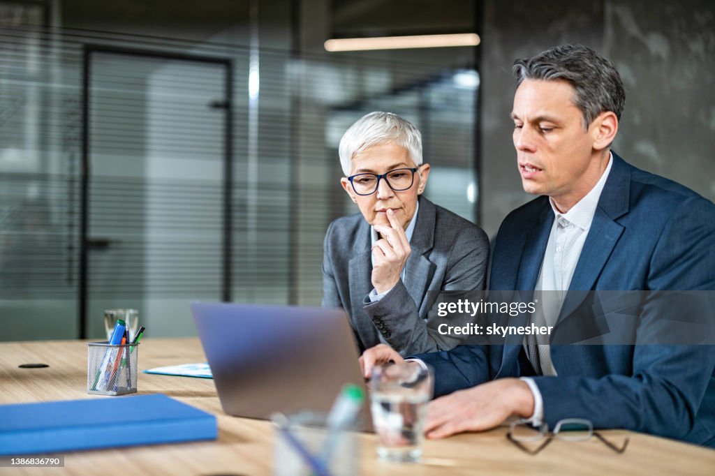 Business colleagues cooperating while working on laptop in the office.