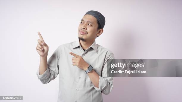 asian muslim man pointing with fingers - happy man pink background stock pictures, royalty-free photos & images