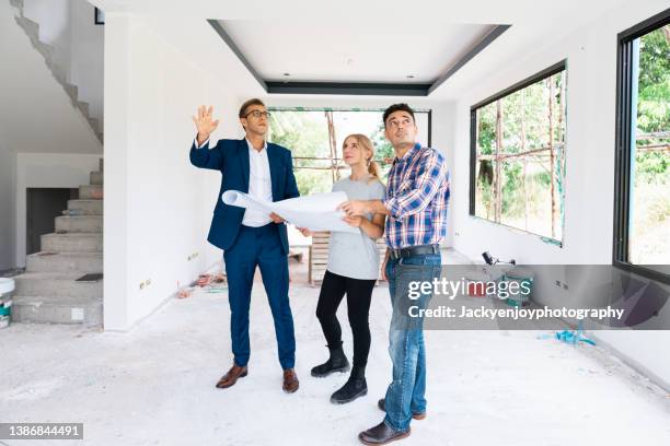 man in suit talking to couple in unfinished building - person in suit construction stock-fotos und bilder