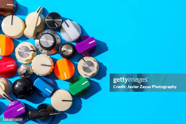 many multi colored knobs on blue background - multi coloured buttons stock pictures, royalty-free photos & images