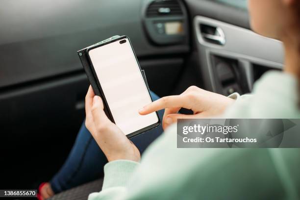 white screen smart phone being used by a young woman on a car - girl looking over shoulder stock pictures, royalty-free photos & images