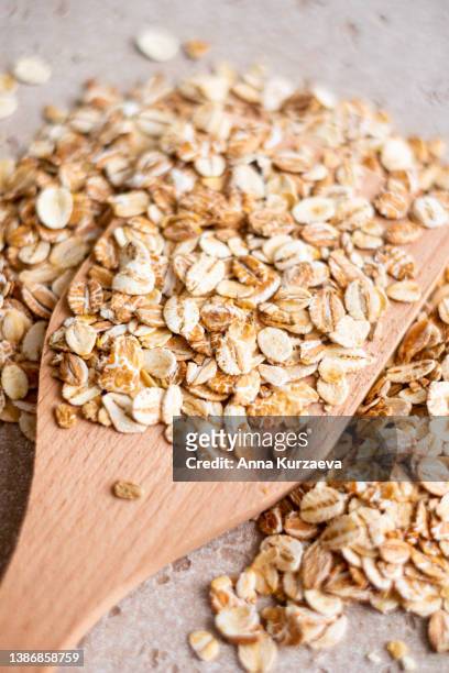 close-up of raw oat flakes in a wooden spoon and on a table, top view. healthy grains. - haferflocken stock-fotos und bilder