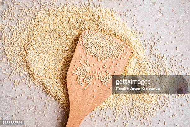 close-up of raw quinoa in a wooden spoon and on a table, top view - quinoa stockfoto's en -beelden