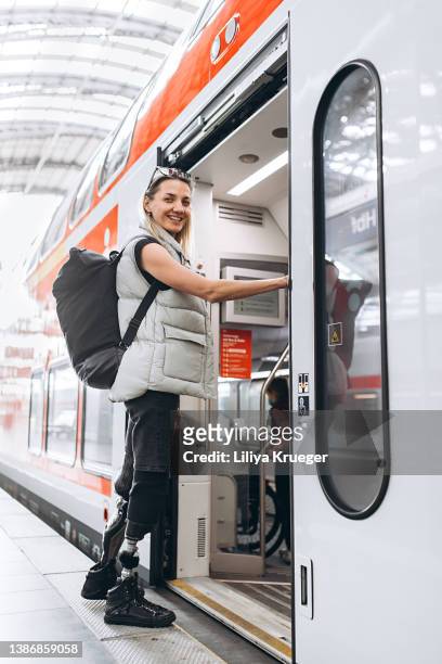 happy beautiful woman with legs prosthesis boarding train. - hessen deutschland stock-fotos und bilder