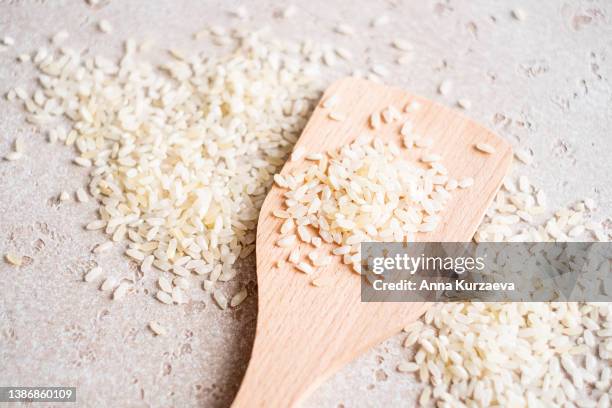 close-up of raw white rice in a wooden spoon and on a table, top view - 稲 ストックフォトと画像