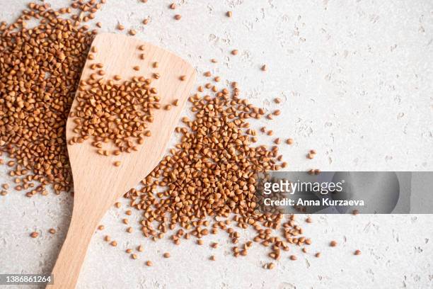 close-up of raw buckwheat in a wooden spoon and on a table, top view - buckwheat ストックフォトと画像