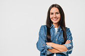 Smiling happy caucasian young woman in denim shirt looking at camera with arms crossed isolated in white background. Toothy smile, dentistry stomatology concept