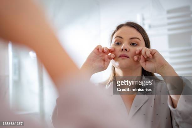 beautiful plus size woman looking at herself in the bathroom - chubby face stockfoto's en -beelden