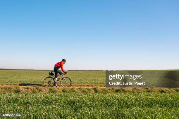 cyclist on gravel track through agricultural fields - road motion bildbanksfoton och bilder