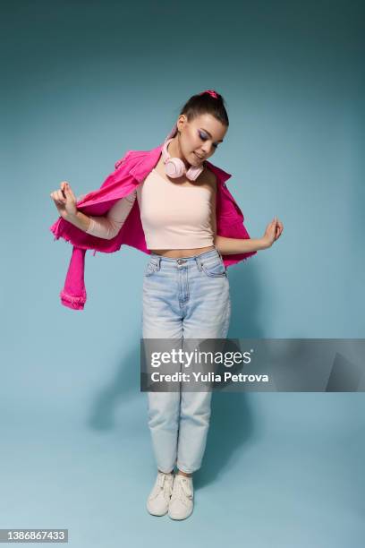 a girl in bright clothes with headphones and bright makeup jumps and smiles on a colored background in the studio - girl jump studio stock pictures, royalty-free photos & images