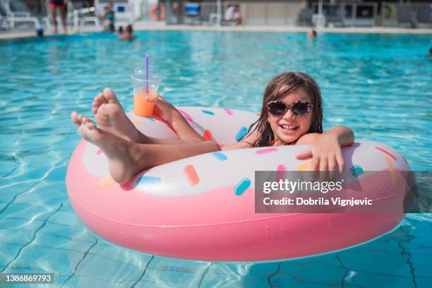 chica con gafas de sol cuando está acostada en un flotador en forma de rosquilla en una piscina - girls sunbathing fotografías e imágenes de stock