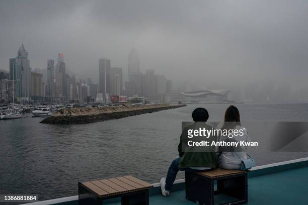 People wearing face masks as a preventive measure against the Covid-19 enjoy a moment at promenade in front of Victoria Harbour on March 21, 2022 in...