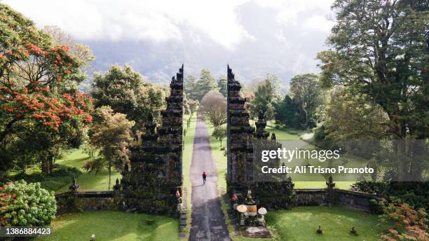 man at vacation walking through the hindu temple in bali, indonesia - bali stockfoto's en -beelden