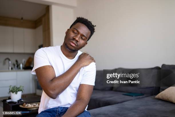 junger afroamerikaner, der sich zu hause krank fühlt - man touching shoulder stock-fotos und bilder