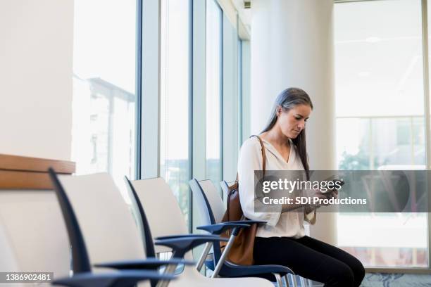 mittelgroße frau sitzt im wartezimmer - waiting room clinic stock-fotos und bilder