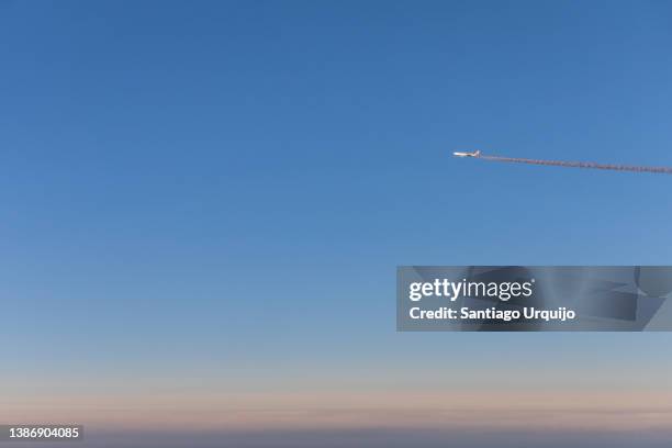 airplane flying above the clouds leaving a smoke trail - sunset with jet contrails stock pictures, royalty-free photos & images