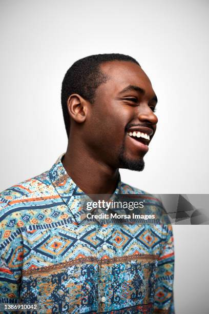 close-up of smiling black man looking away. confident young male is wearing casuals. he is against white background. - portrait white background male foto e immagini stock