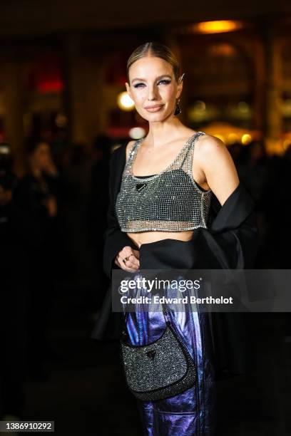 Leonie Hanne wears a silver and black triangle pendant earring from Prada, earrings, a black square neck cropped top, a silver mesh cropped tank-top...