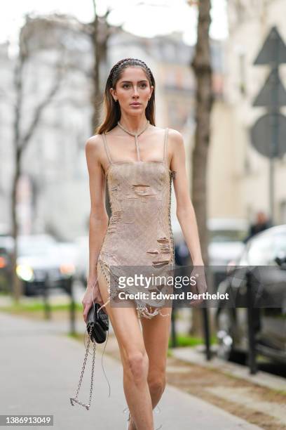 Teddy Quinlivan wears a gold rhinestones with square-neck / necklace / sleeveless / ripped short tube dress, a black shiny leather handbag from Louis...