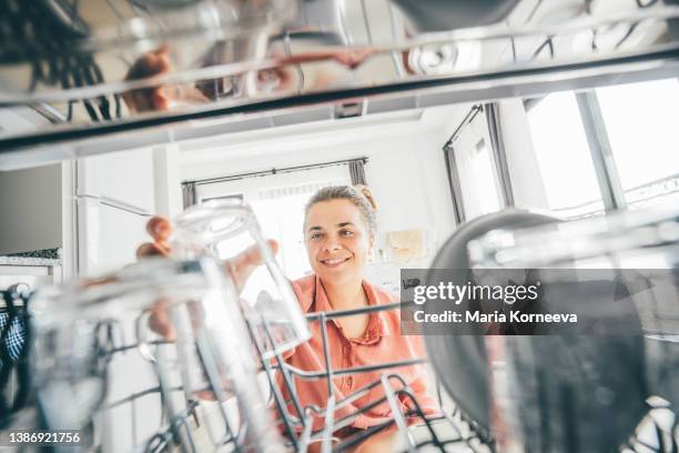 woman putting dishes in dishwasher. 
view from inside dishwasher. - stereotypical housewife bildbanksfoton och bilder