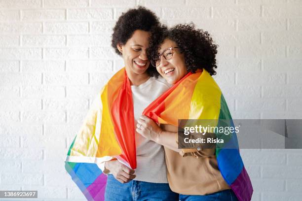 lesbische frauen mit regenbogenfahne bedeckt - lgbtqia pride event stock-fotos und bilder