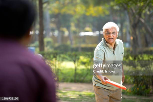 happy senior man throwing frisbee disc at park - flying disc stock pictures, royalty-free photos & images