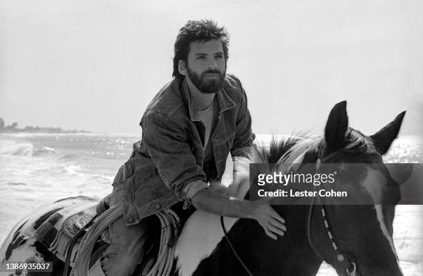 American musician, singer and songwriter, Kenny Loggins, rides his horse at the beach circa 1985 in Los Angeles, California.