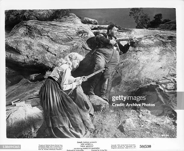 Marilyn Maxwell holding gun on mountainside with another gunman in a scene from the film 'New Mexico', 1950.