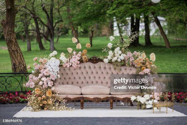 view of a sofa decorated with flowers with park on the background. - garden decoration fotografías e imágenes de stock