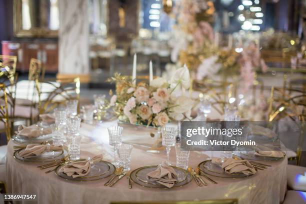 view of wedding tables with flower arrangements, golden cutlery, candles and plates with white napkins. - dinner reception for the wedding of lee radziwill and herb ross stockfoto's en -beelden