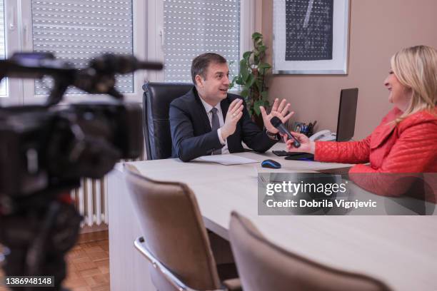 geschäftsmann, der gestikuliert und lächelt, wenn er ein medieninterview hat - chef redakteur stock-fotos und bilder