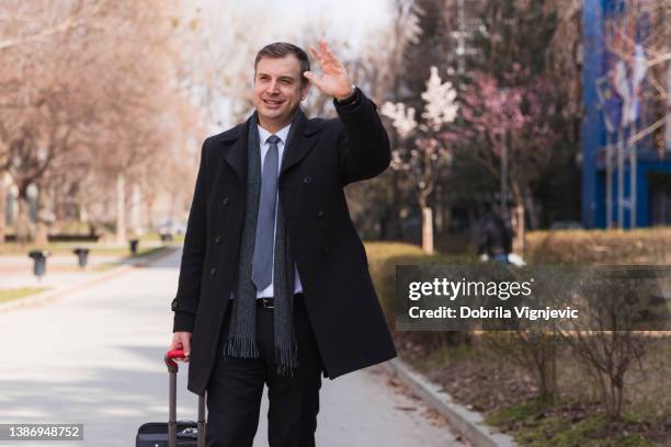 homme d’affaires heureux agitant la main en quittant l’hôtel - waving hands goodbye photos et images de collection