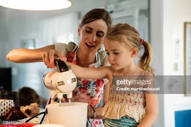 mother and young daughter baking a cake at home. - baking stockfoto's en -beelden