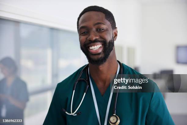 doctor in scrubs standing in hospital corridor - doctor scrubs stock pictures, royalty-free photos & images