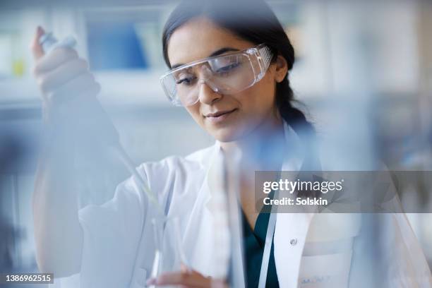 young female scientist working in laboratory - lunette de protection photos et images de collection
