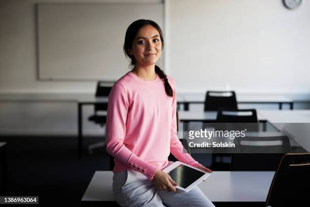 female teacher sitting in classroom holding digital tablet - school denmark stock pictures, royalty-free photos & images