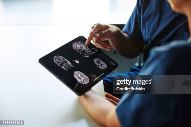 two doctors looking at x-ray images on digital tablet - scansione medica foto e immagini stock