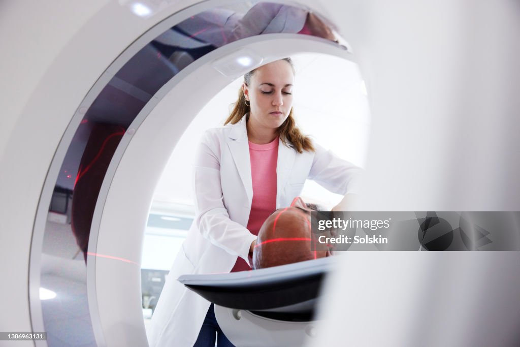 Female radiologist helping patient in medical x-ray scanner