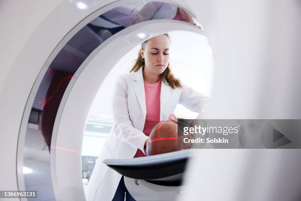 female radiologist helping patient in medical x-ray scanner - radiologist 個照片及圖片檔